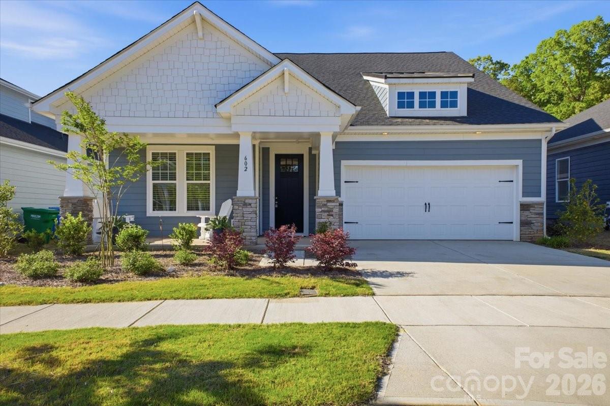 Blue-gray house with white gables, stone porch columns, and a wide two-car garage.