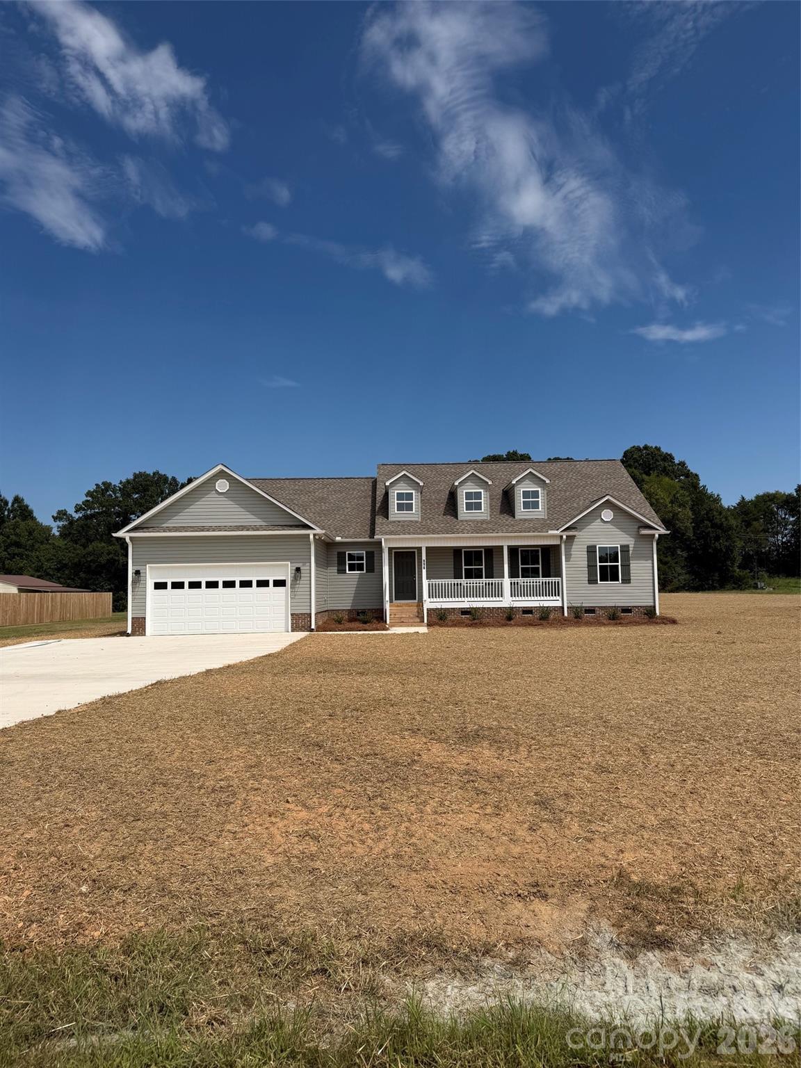 Gray detached house with a two-car garage, covered porch, and three dormer windows.