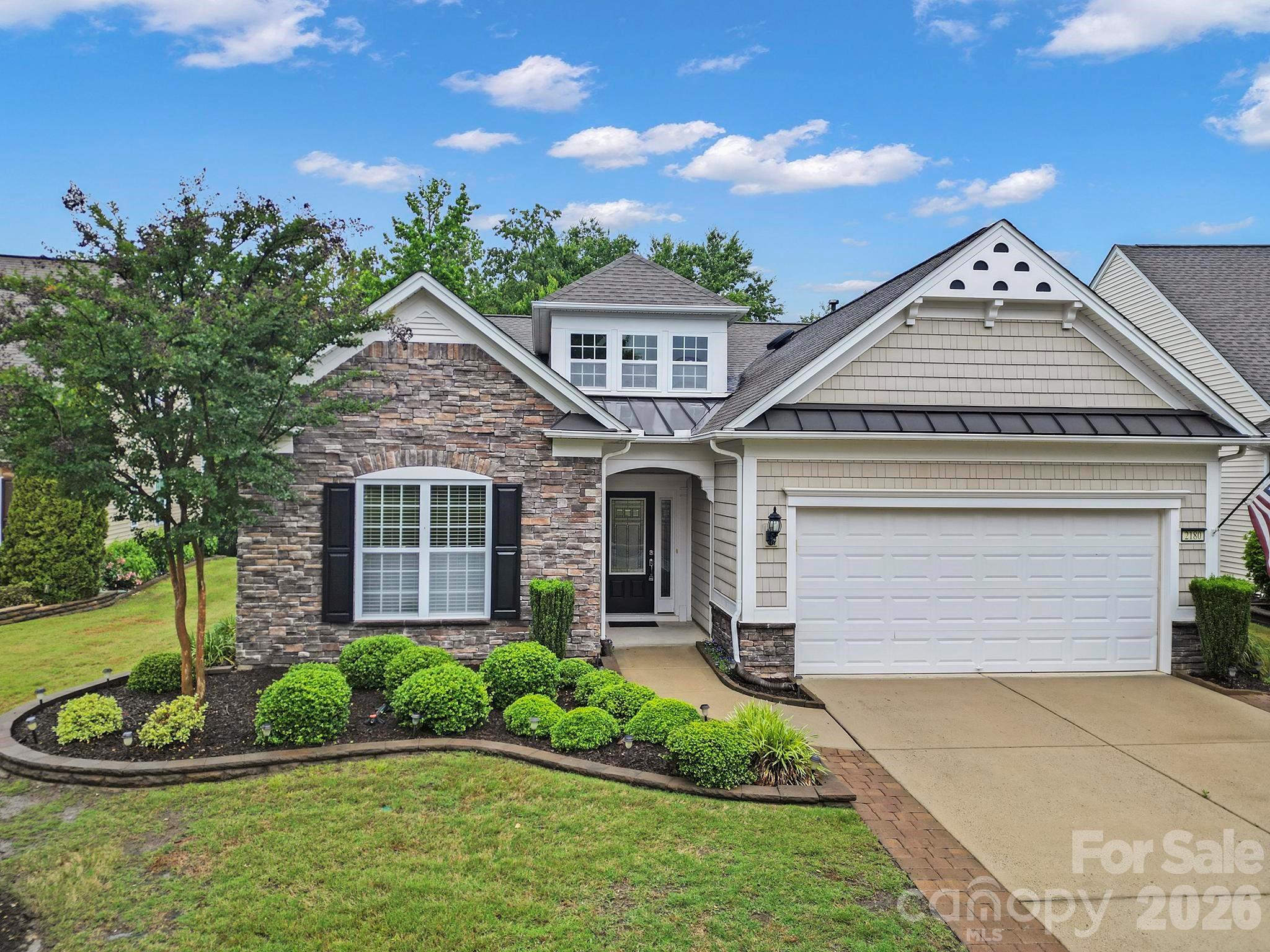 Home exterior with stone facade, landscaped front yard, and attached garage.