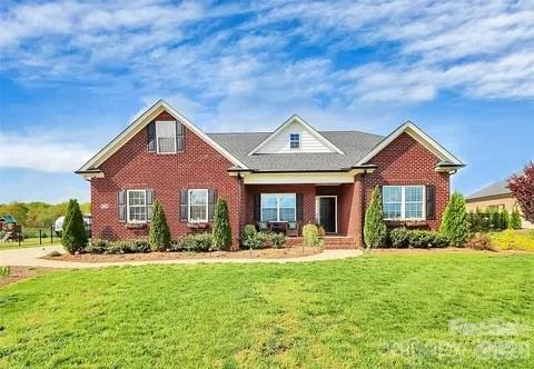 Red brick house with multiple gables, covered entry, and broad green front lawn.