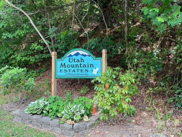Utah Mountain Estates community sign among trees and a landscaped stone planter.