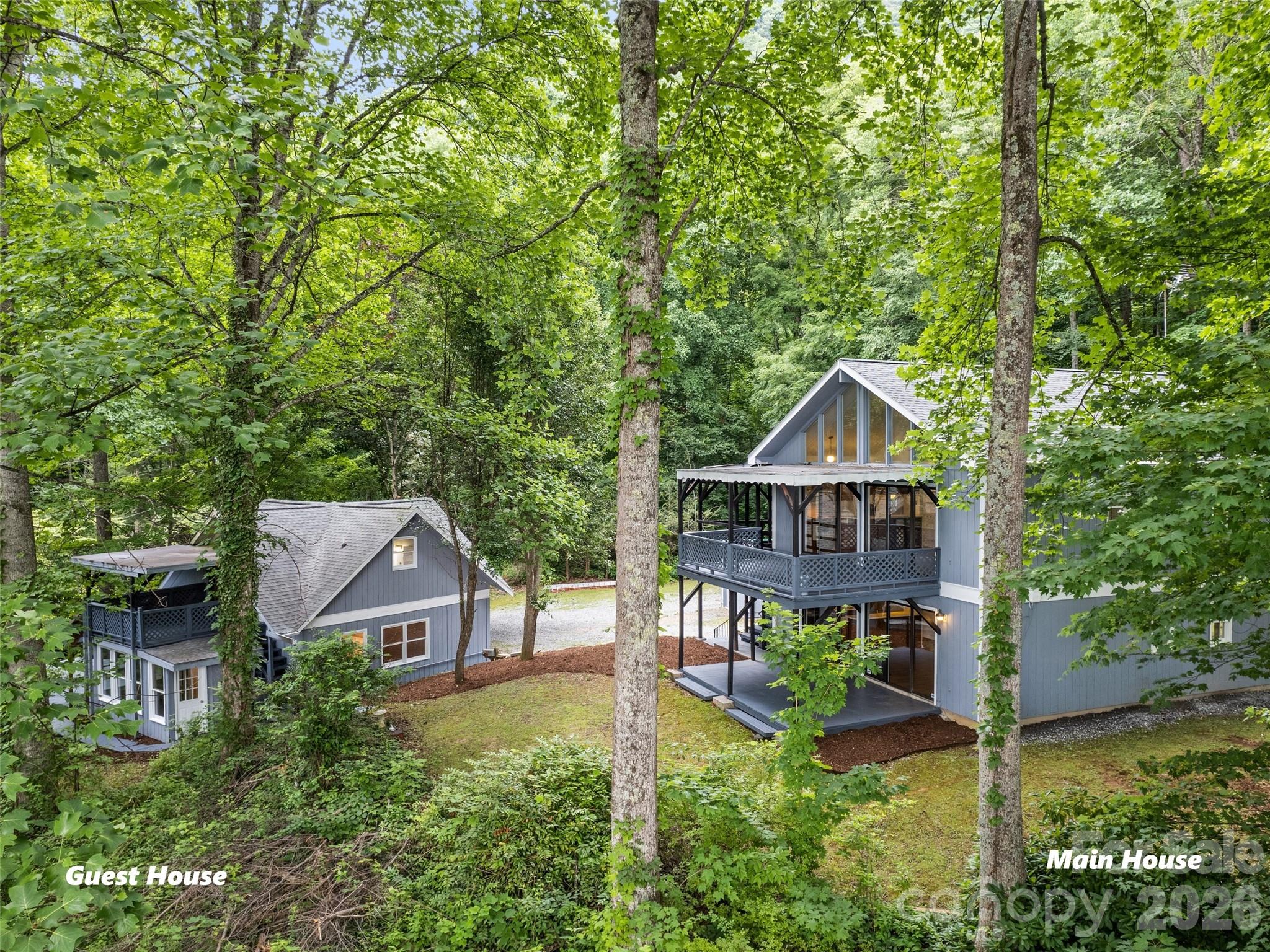 Main house and guest house nestled among trees, with raised decks and blue-gray siding.