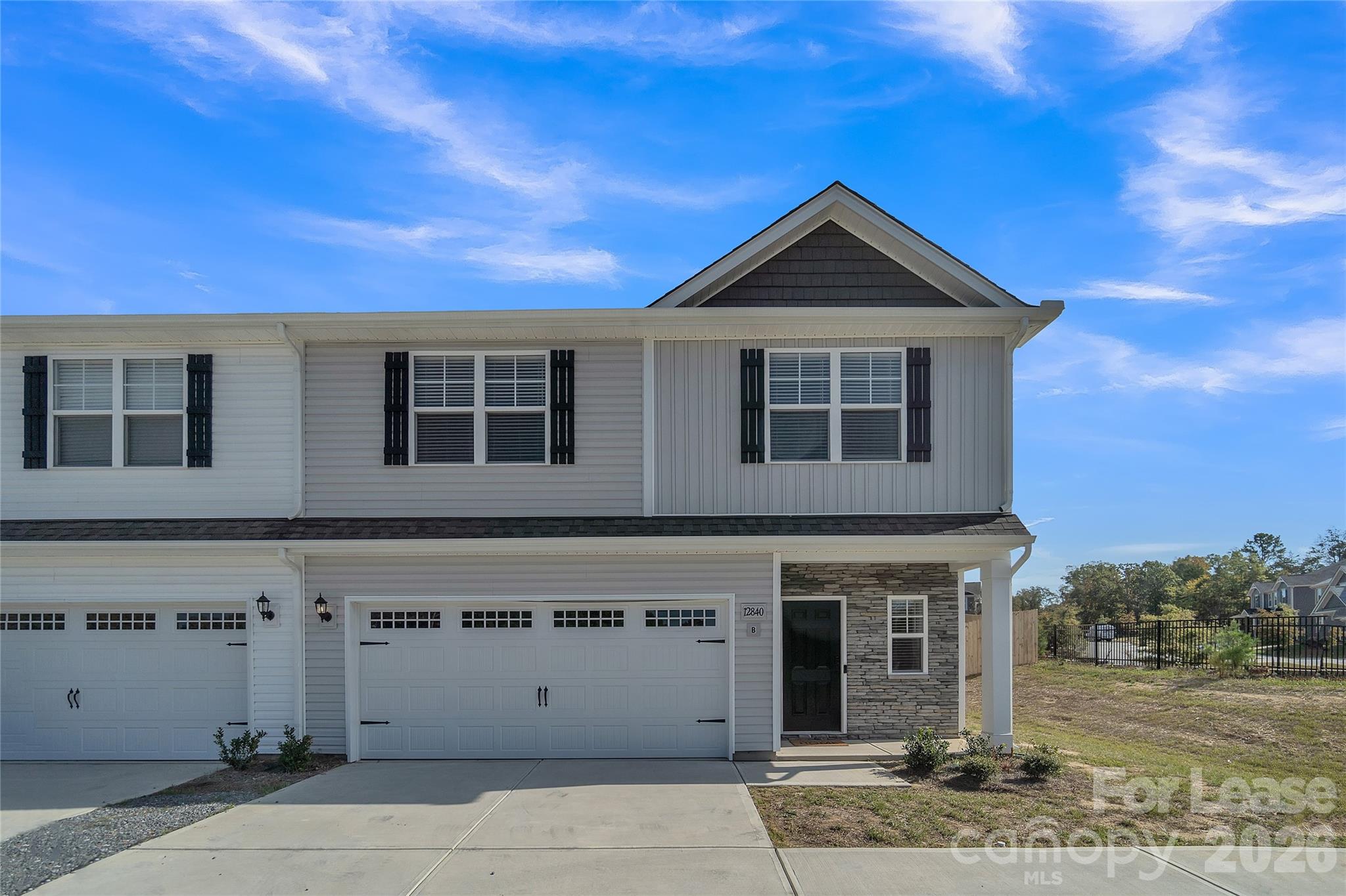 Two-story house with a stone-accented entry, two garage doors, and a wide concrete driveway.