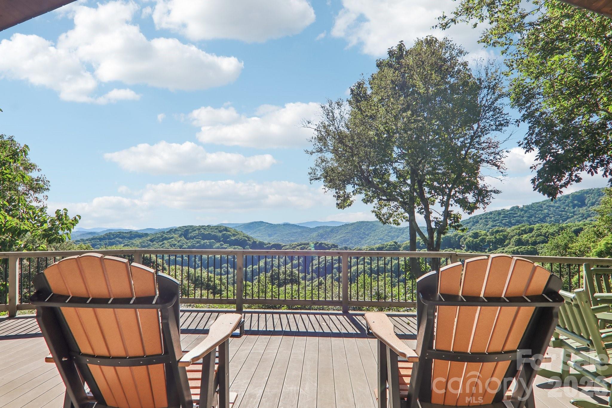 Deck with orange Adirondack chairs overlooking forested mountain ridges.