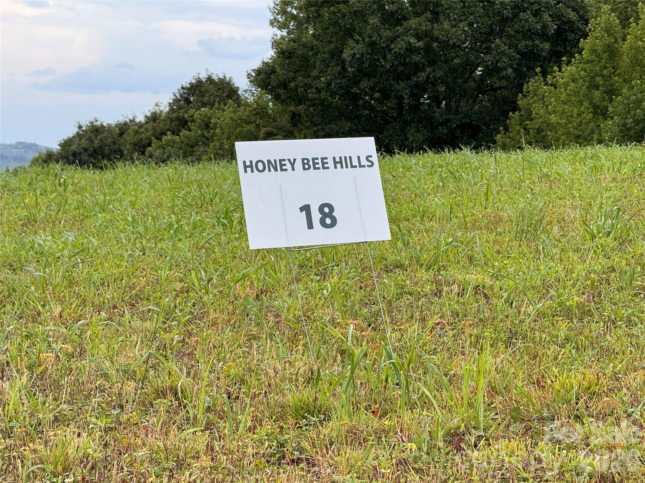 Grassy vacant lot marked by a Honey Bee Hills sign with lot number 18.