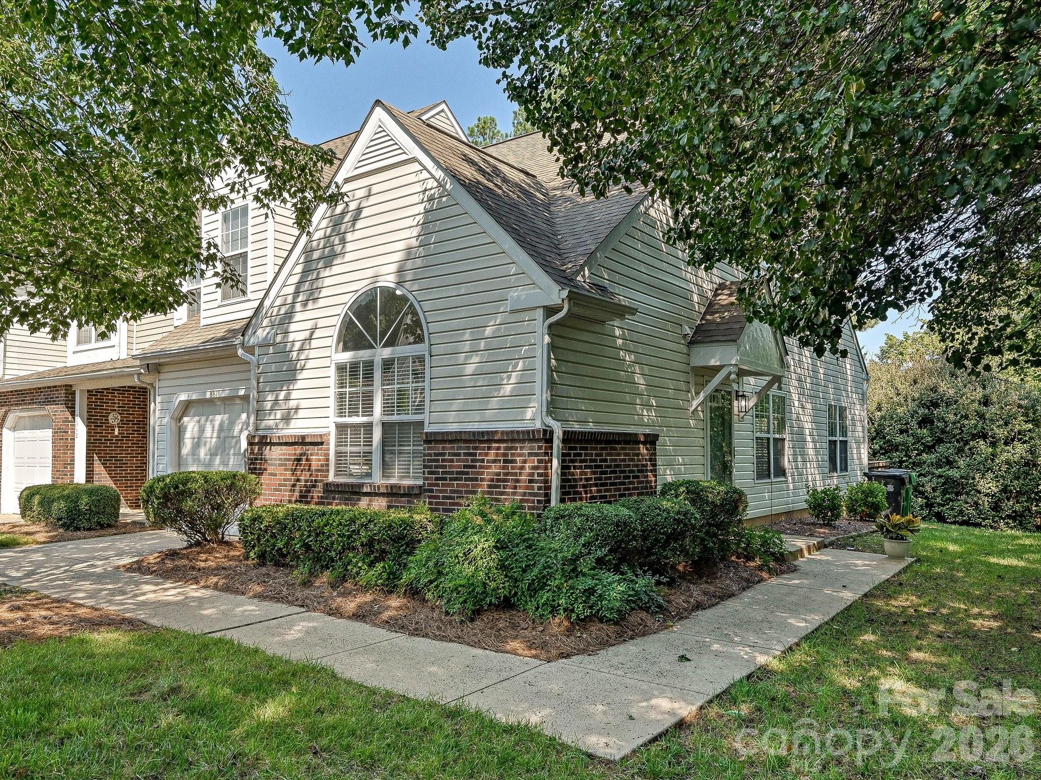 Home at 8810 Scotch Heather Way with pale siding, brick accents, and a large arched window.