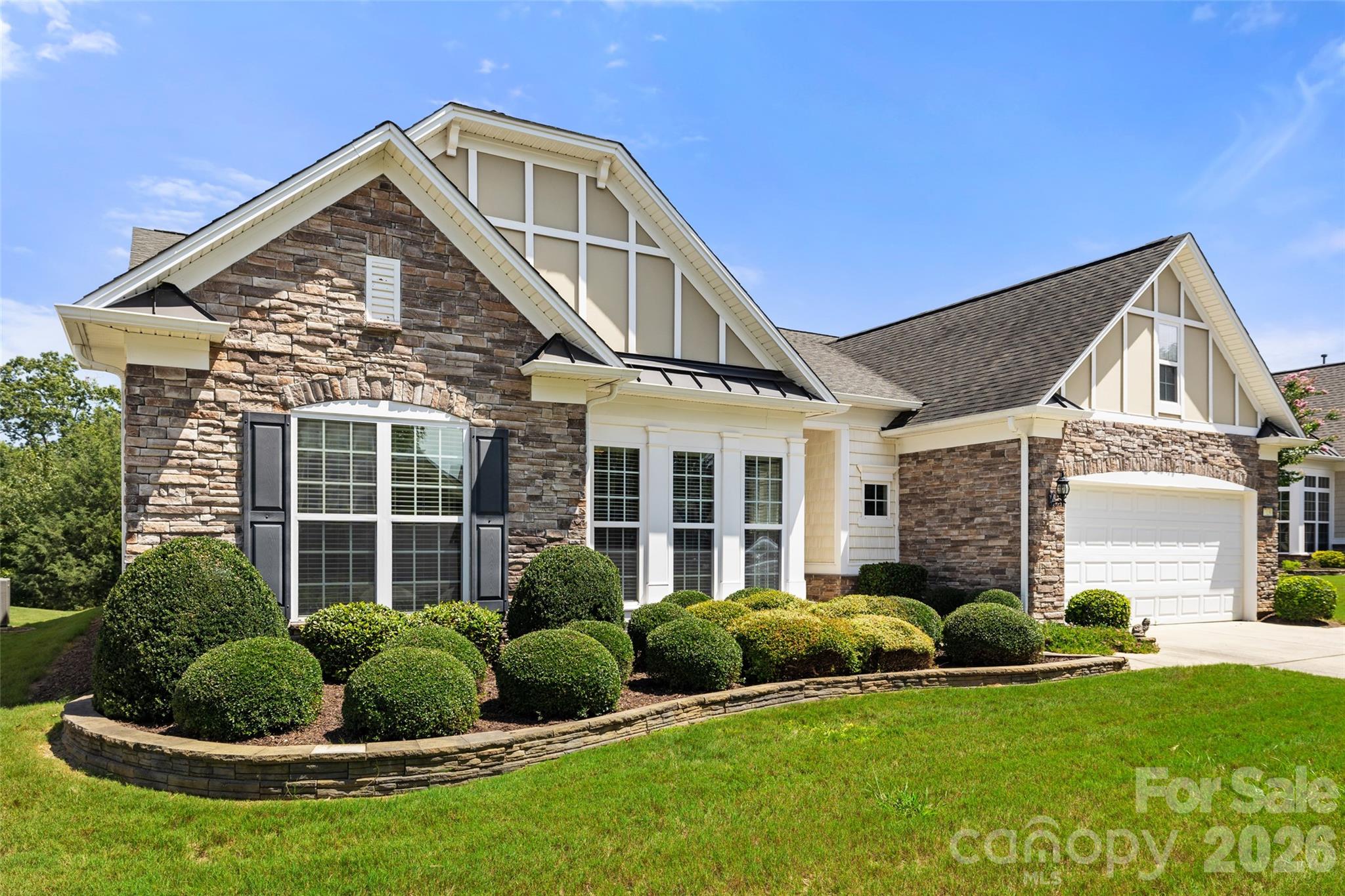 Stone-and-cream two-story home with a two-car garage and manicured landscaping.