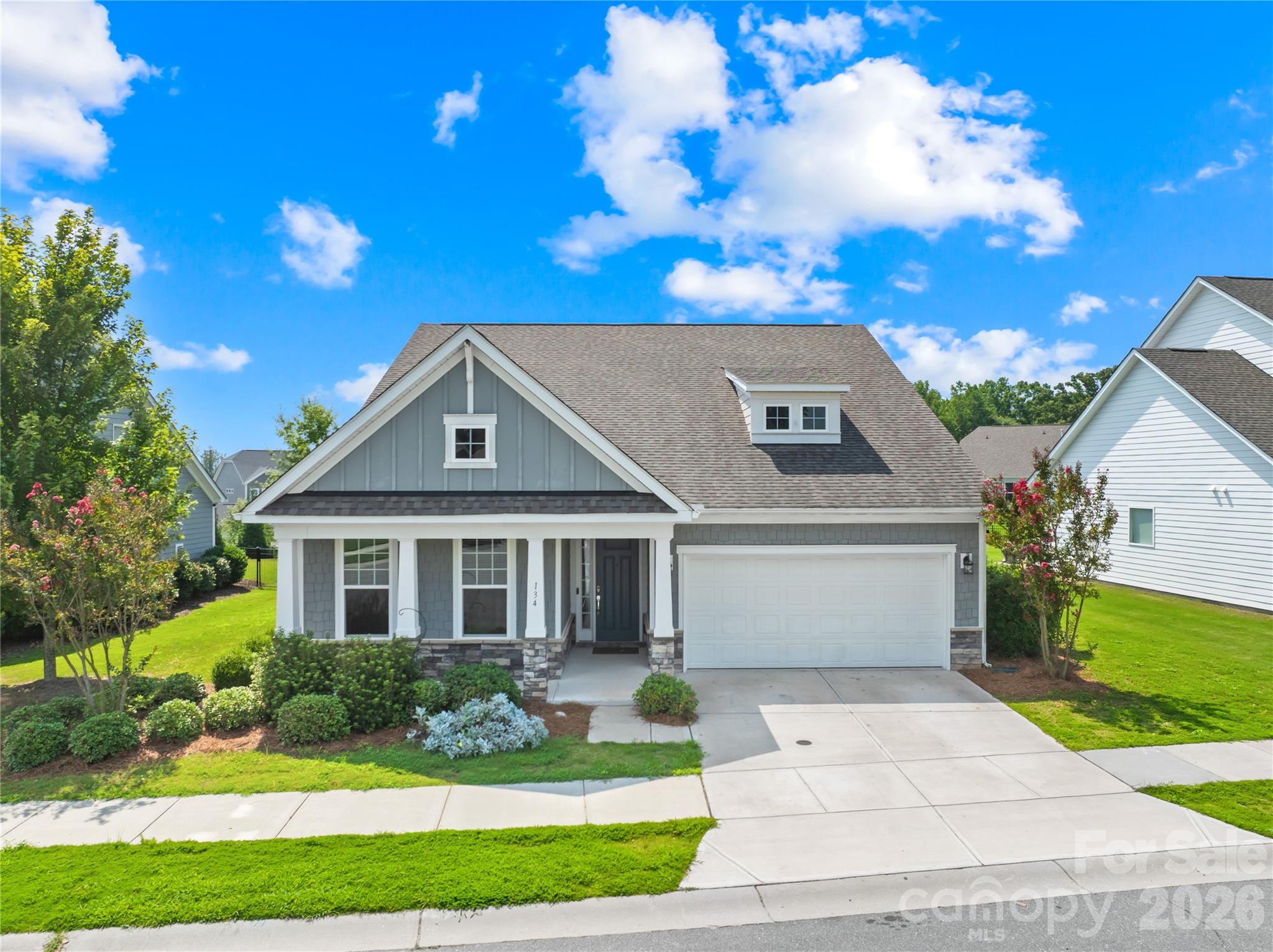 Gray two-story house with white trim, a gabled roof, attached garage, and landscaped front yard.