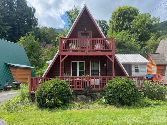 Red A-frame cabin with a wide front porch, upper balcony, and smaller cabins on either side.