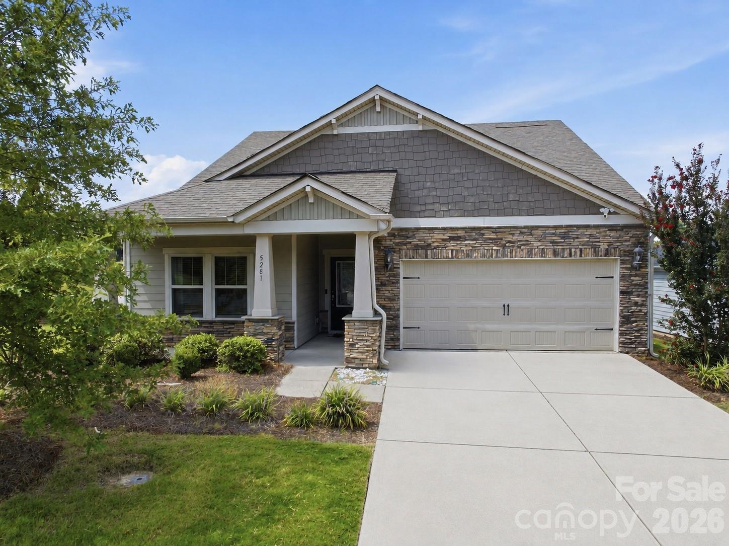 Gray single-story home with stone accents, covered entry, and a wide two-car garage.