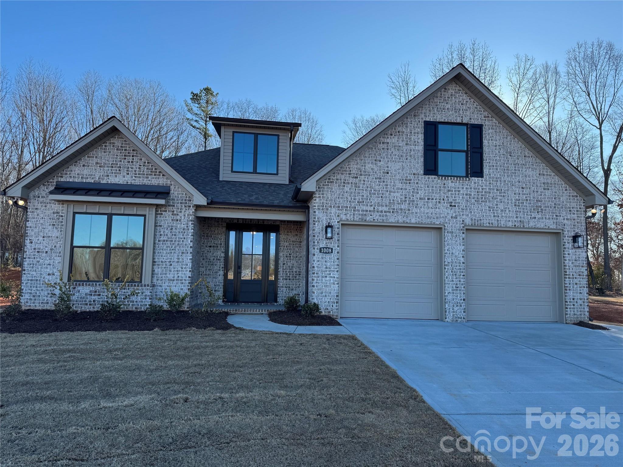 Gray-brick home with two-car garage, prominent gables, and a broad concrete driveway.
