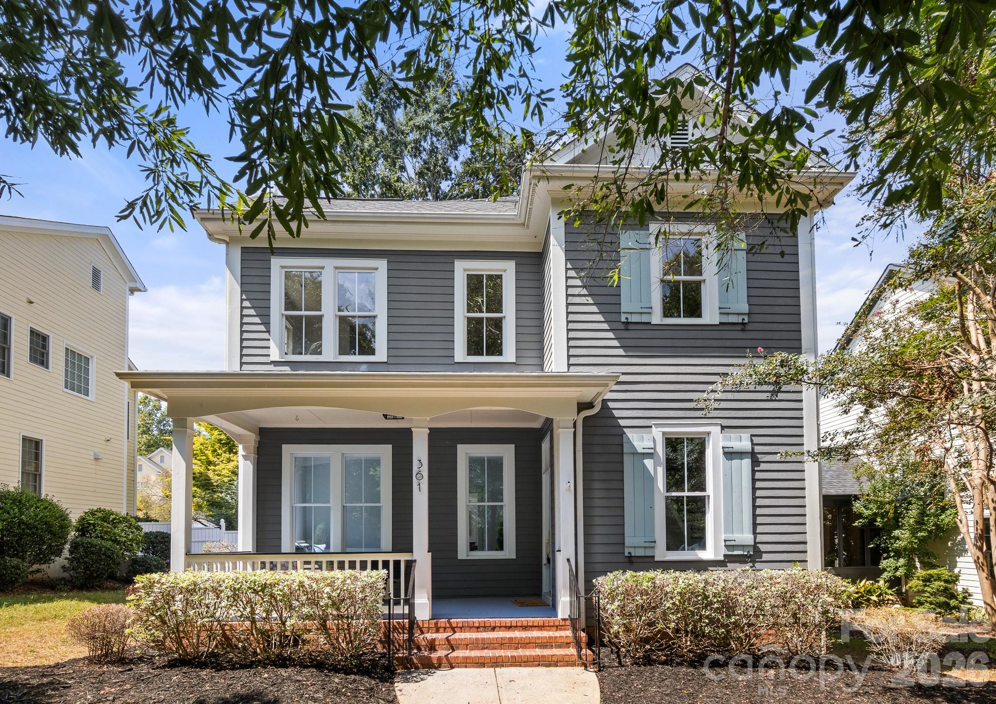 Gray two-story house with pale blue shutters, a covered porch, and brick steps.