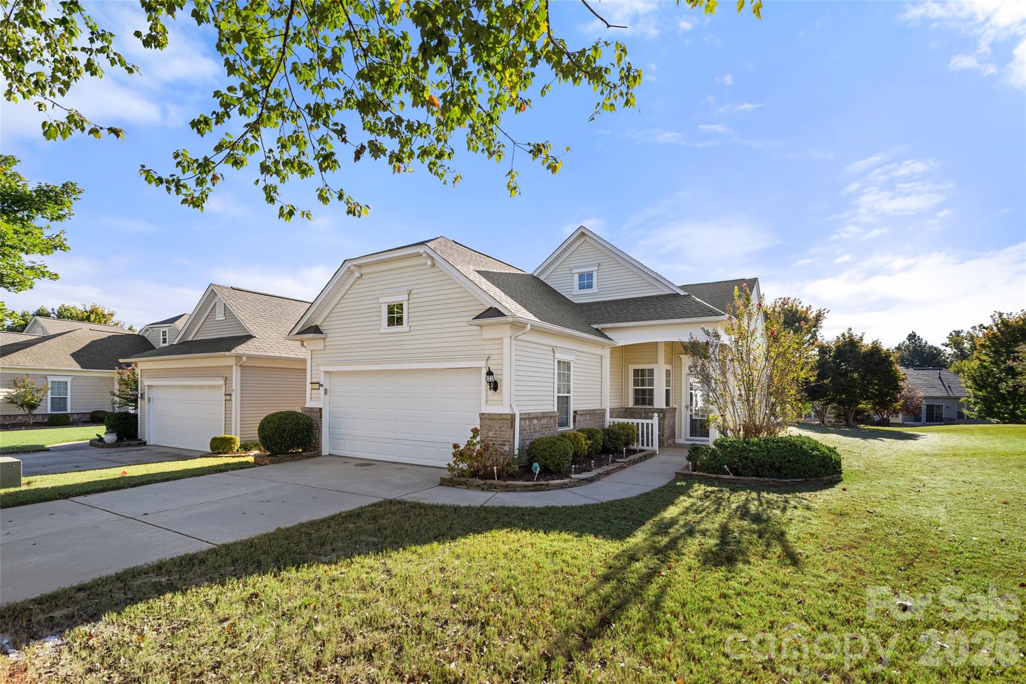 Light-colored gabled home with attached garages, a covered entry, and landscaped lawn.