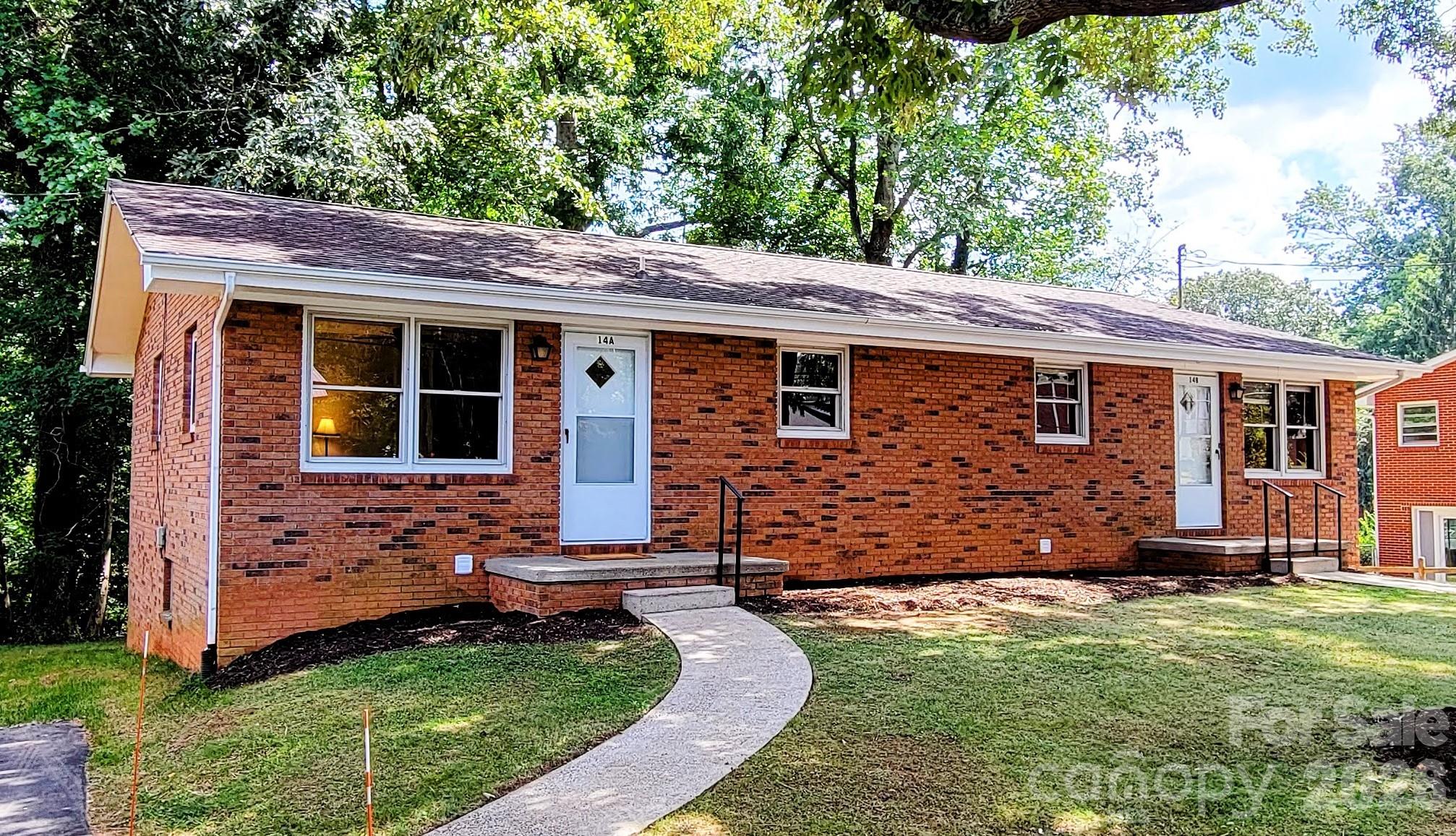 Red-brick duplex with two white entry doors and a curved front walkway.