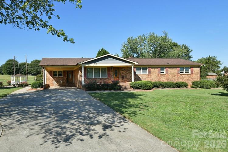 Single-story brick ranch house with a broad driveway and front lawn.