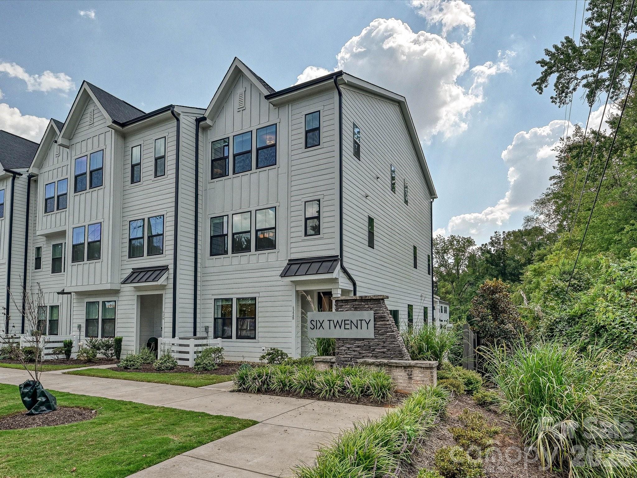 White-sided townhomes with landscaped grounds and a stone SIX TWENTY entrance sign.