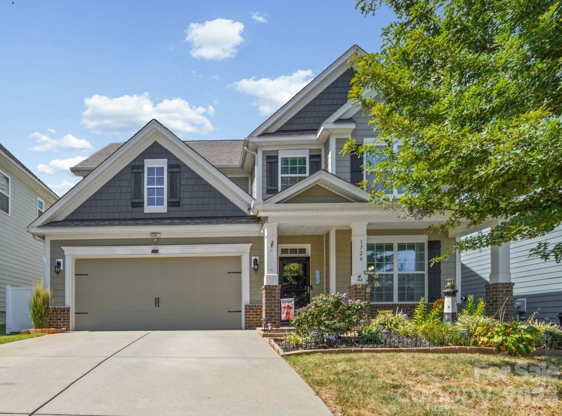 Gray two-story home with a double garage, covered porch, and landscaped front garden.