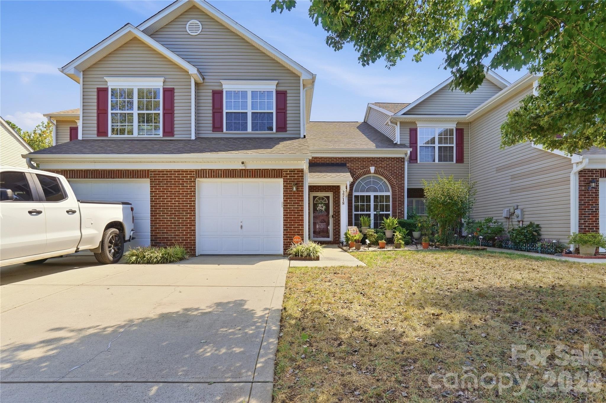 Two-story brick-and-siding home with red shutters, attached garage, and a white pickup in the driveway.