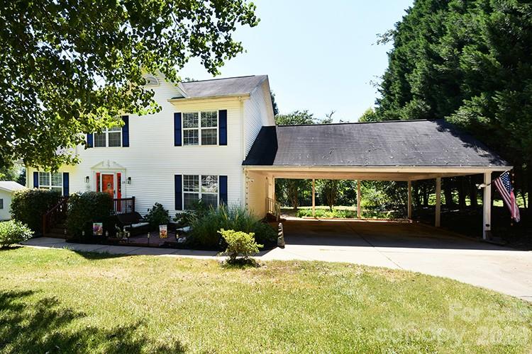 White two-story house with a red front door and a long covered carport.