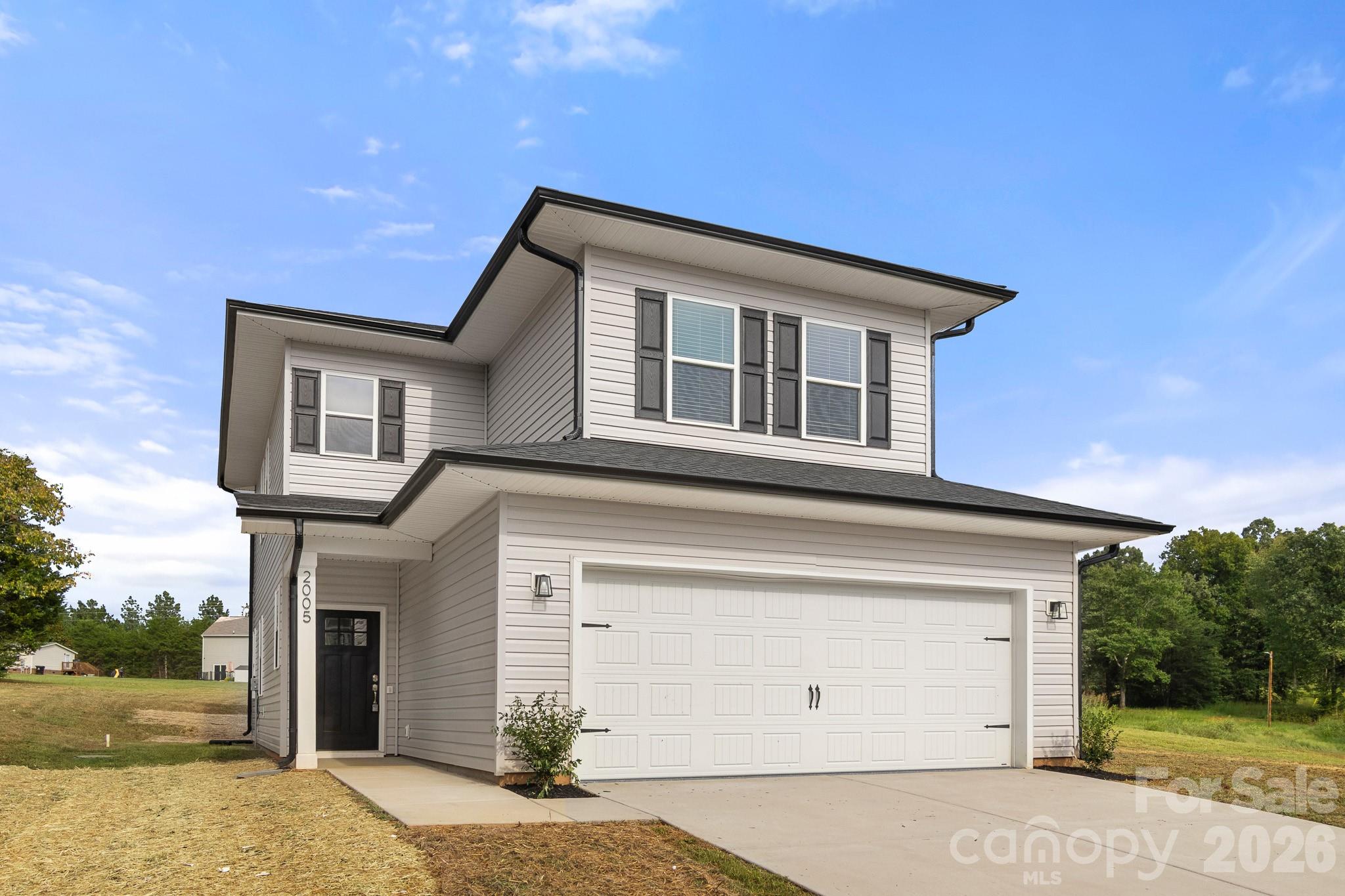 Two-story gray house with dark shutters and a large white double garage door.