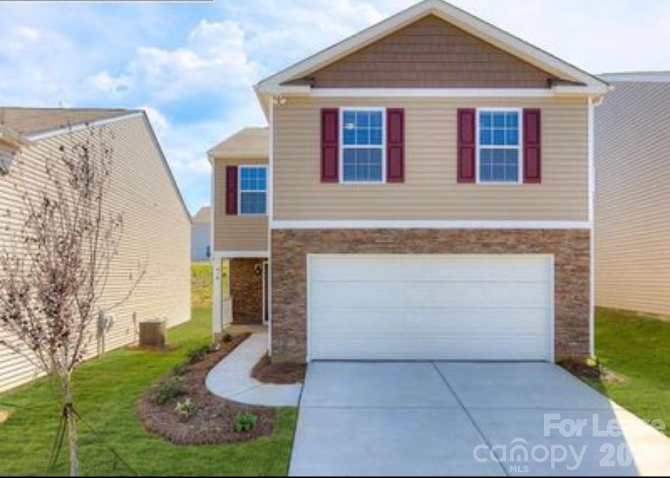 Two-story beige house with red shutters, stone-veneer facade, and double garage.