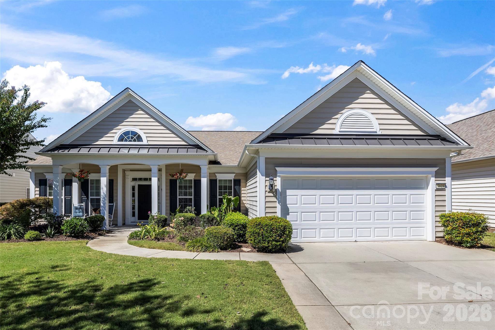 Light gray home with a two-car garage, covered porch, and landscaped front yard.