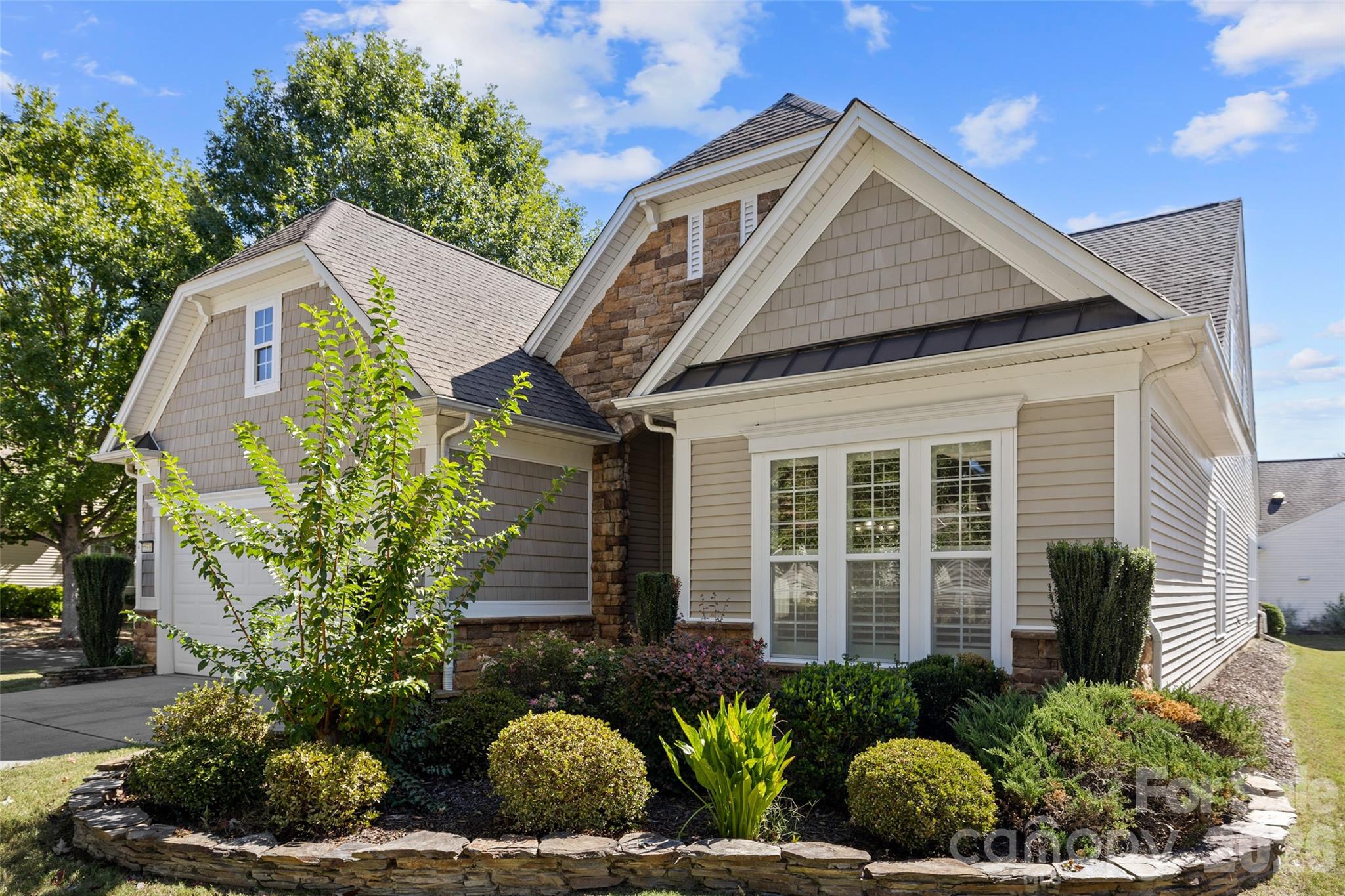Gabled house with stone accents, a garage, and landscaped front garden.