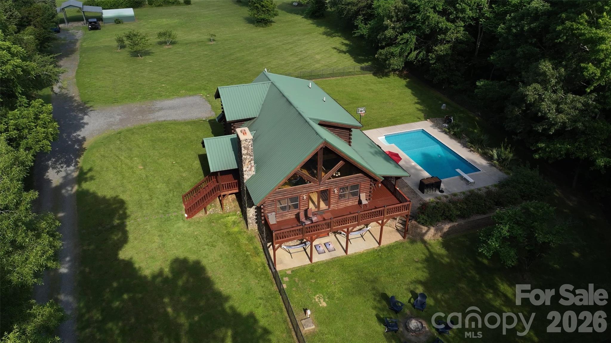 Aerial view of a log cabin with a green roof, elevated decks, and a swimming pool.