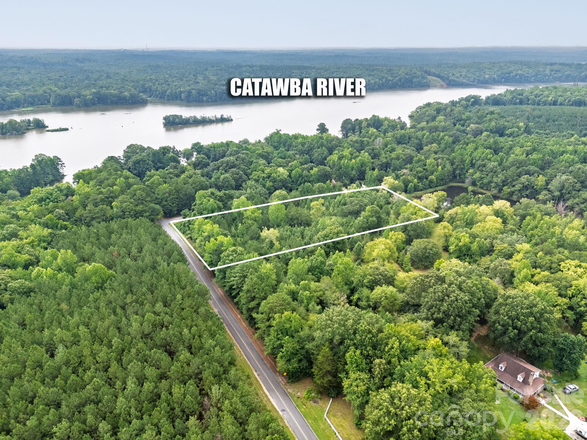 Aerial view of a wooded parcel outlined beside a road, with the Catawba River beyond it.