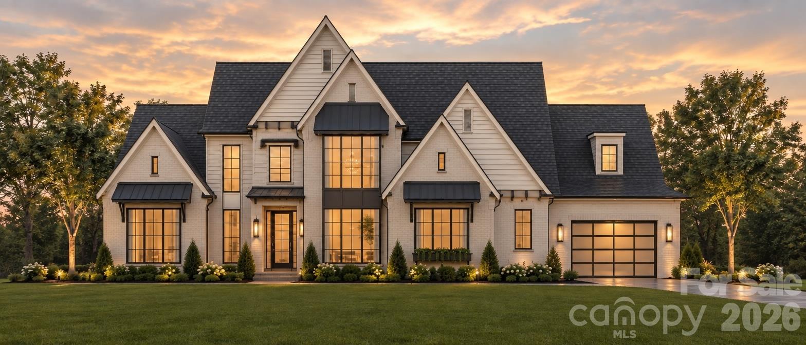 White two-story house with prominent gables and glowing windows at sunset.