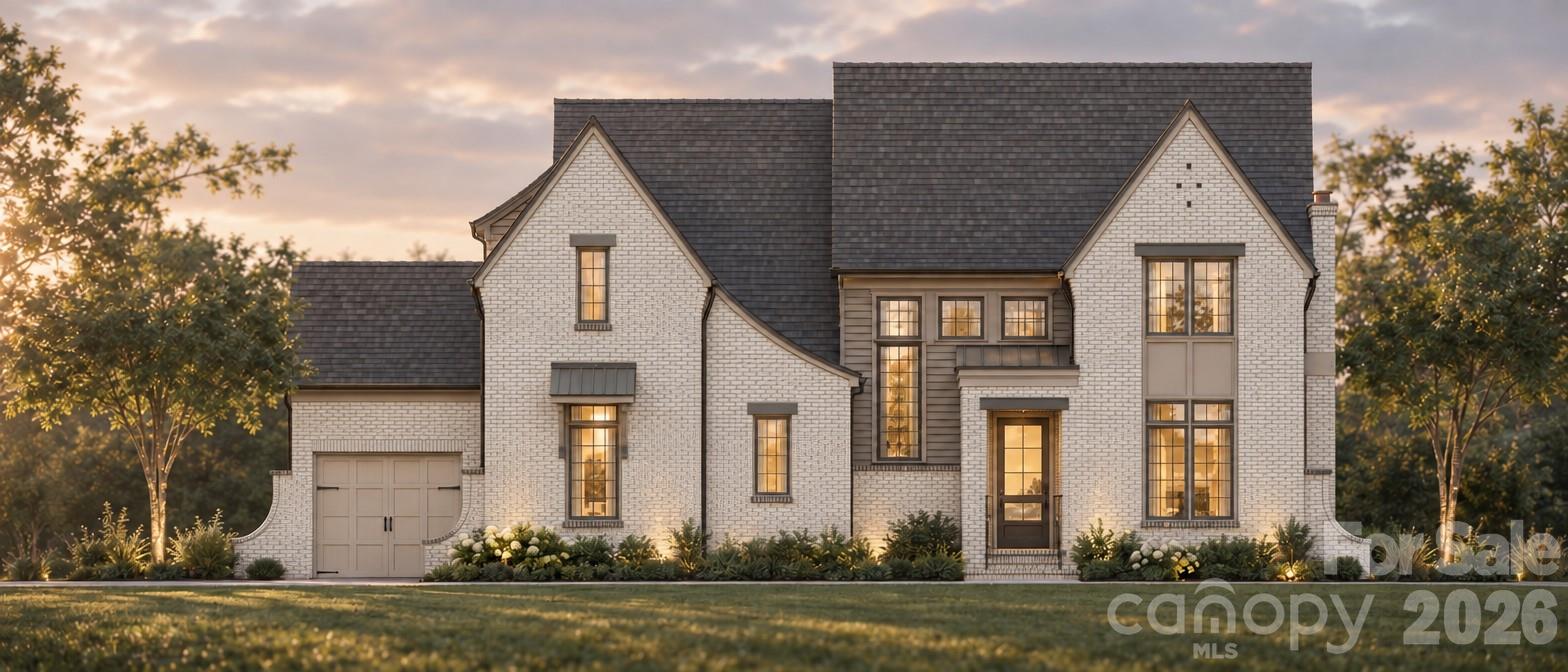 White-brick two-story house with a dark roof, tall windows, and attached garage at golden hour.