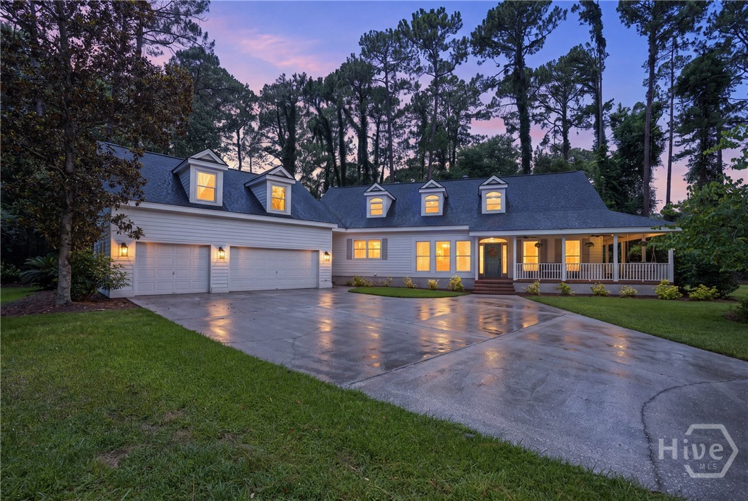 Gray house with multiple dormers, a two-car garage, and a covered porch at dusk.