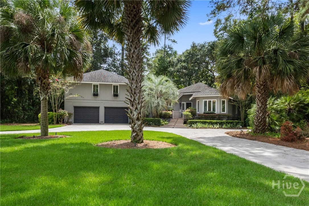 Home with a two-car garage, broad driveway, and mature palms across the front lawn.
