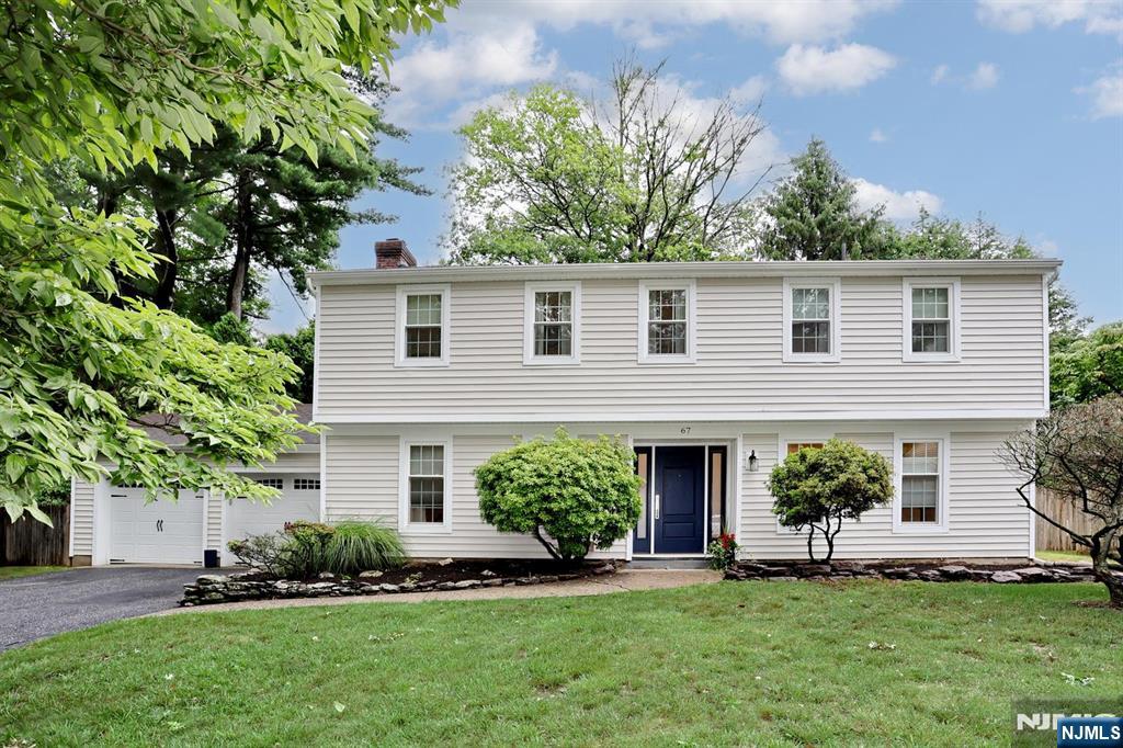 White two-story house with a blue front door, attached garage, and landscaped lawn.