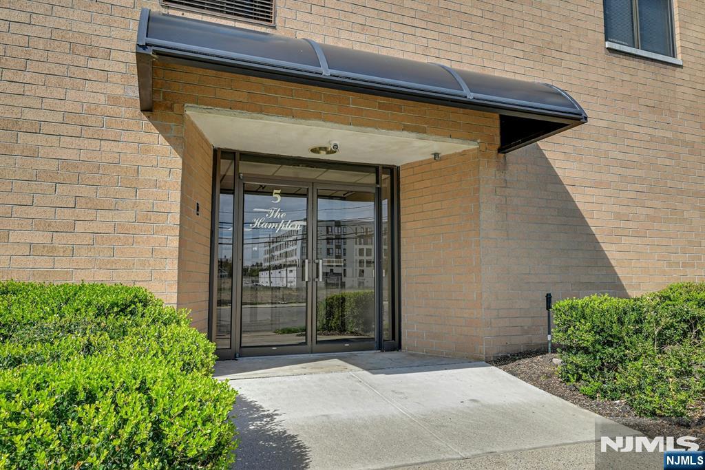 The Hampton building entrance with a curved canopy, glass doors, and brick facade.