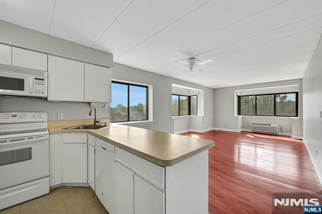 Vacant open-plan kitchen and living area with a peninsula counter and large windows.