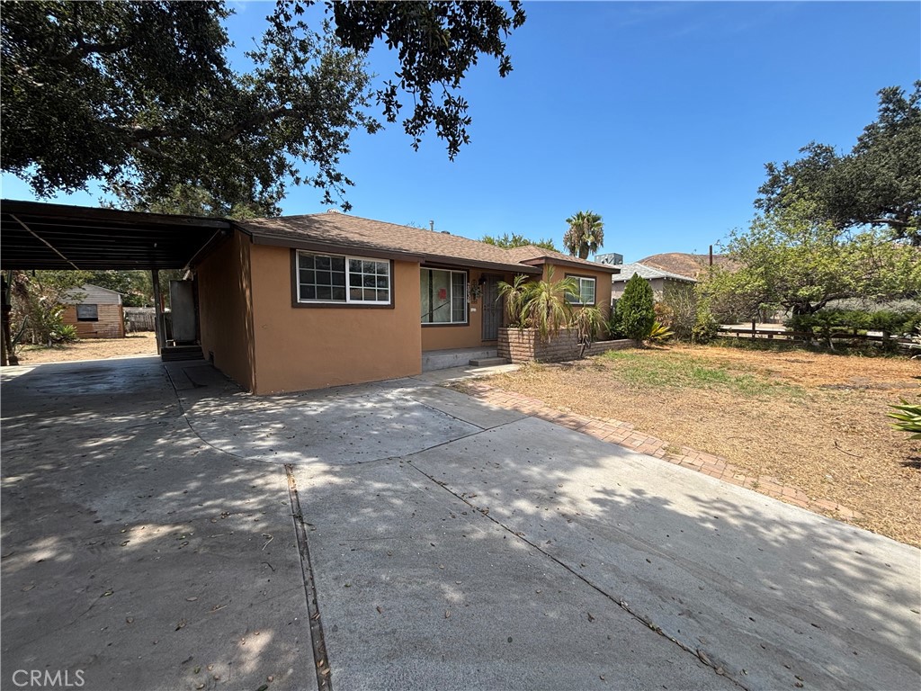 Single-story tan house with a covered carport and broad concrete driveway.