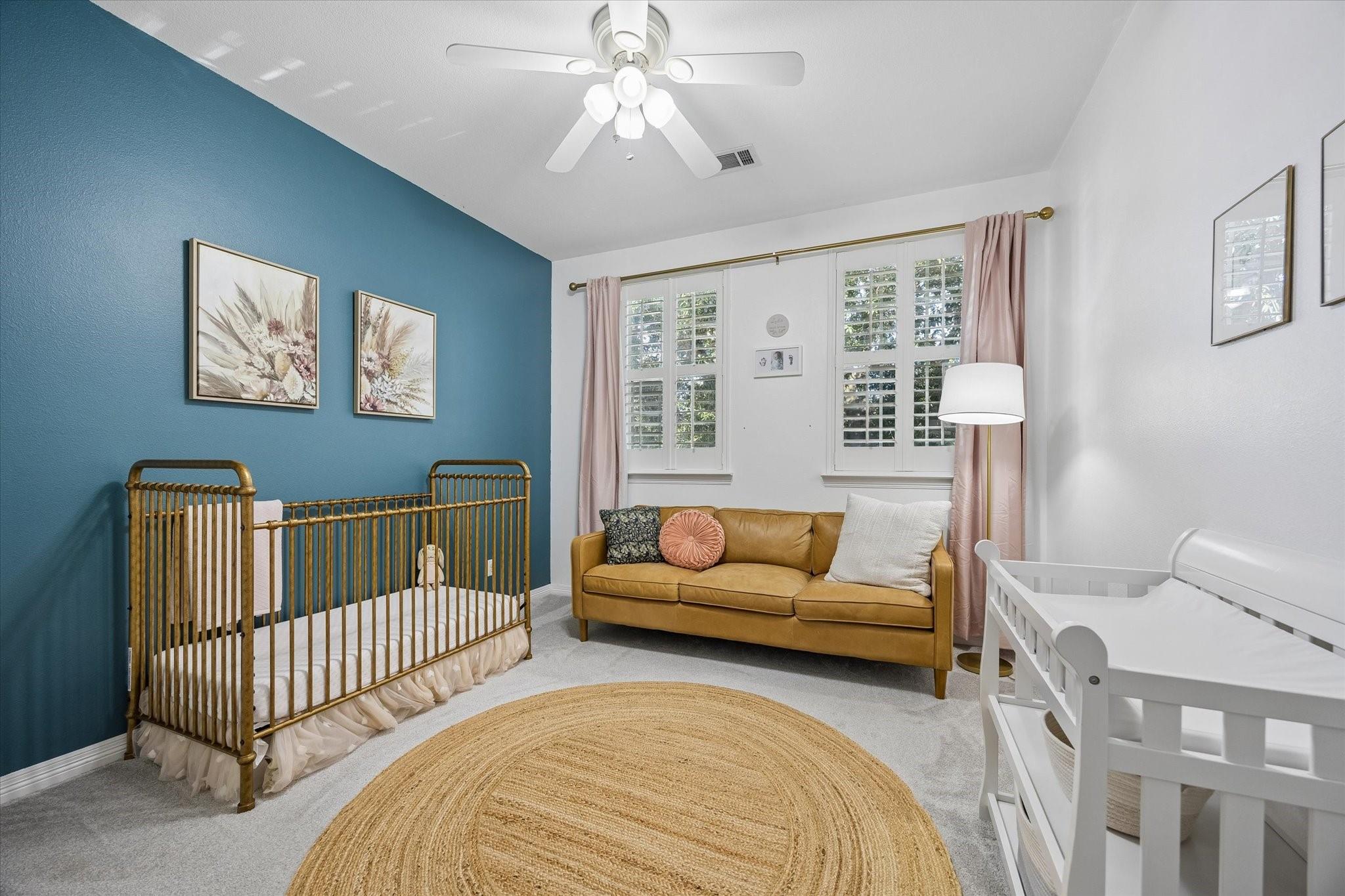 Nursery with brass crib, white crib, and mustard sofa against a teal accent wall.