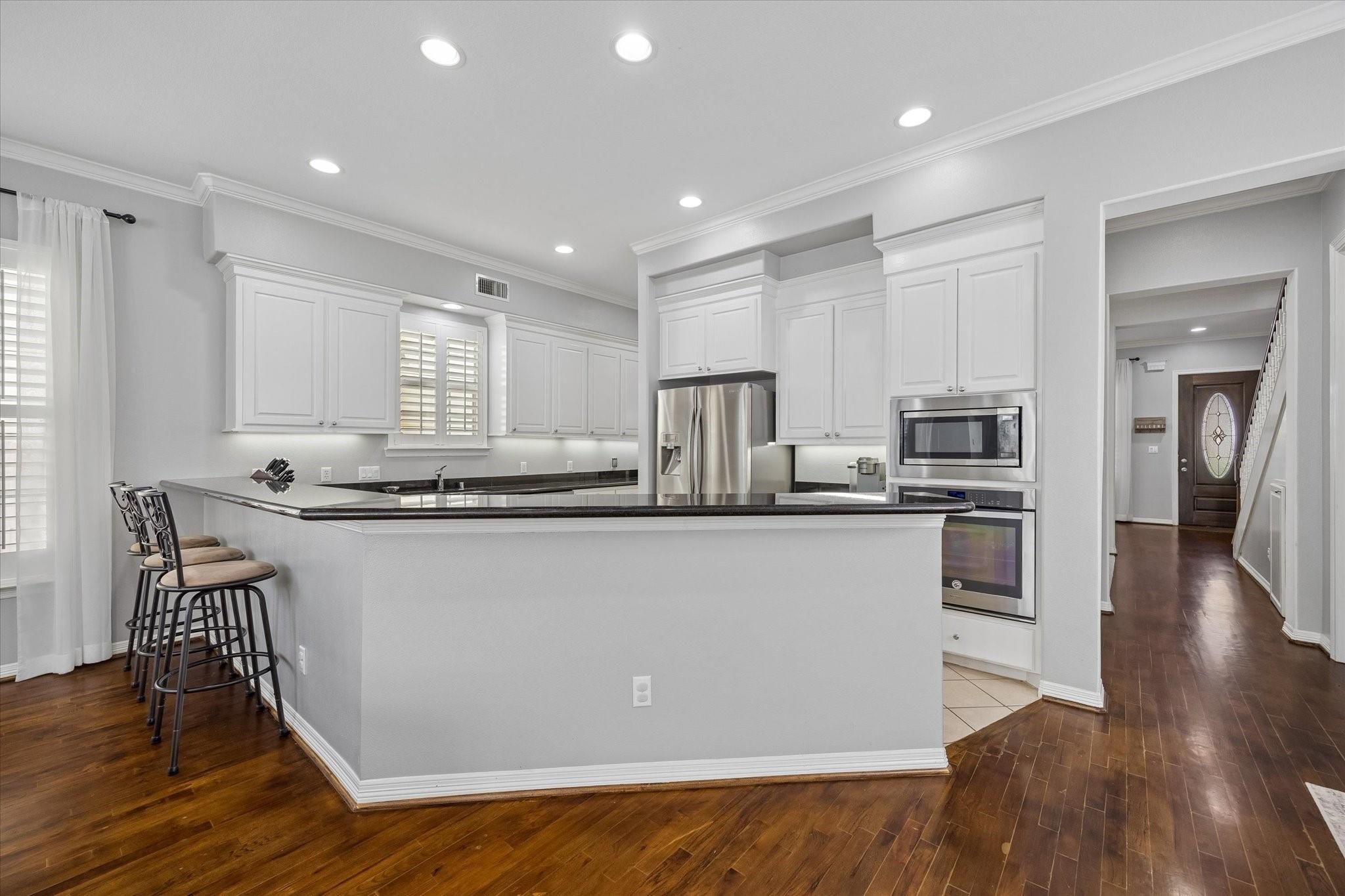 Kitchen with white cabinetry, stainless appliances, and a large breakfast island with bar stools.