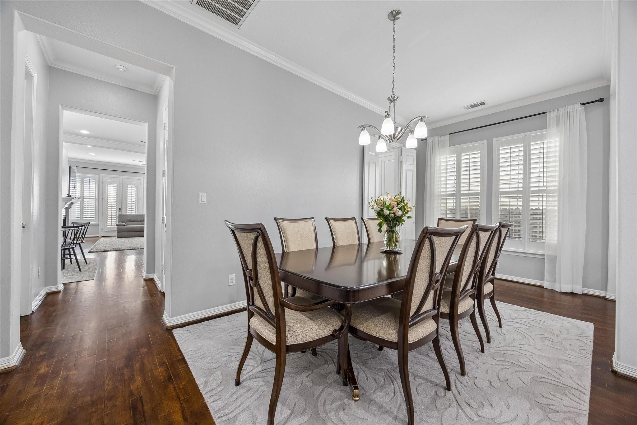 Dining room with a dark wood table, upholstered chairs, and plantation shutters.