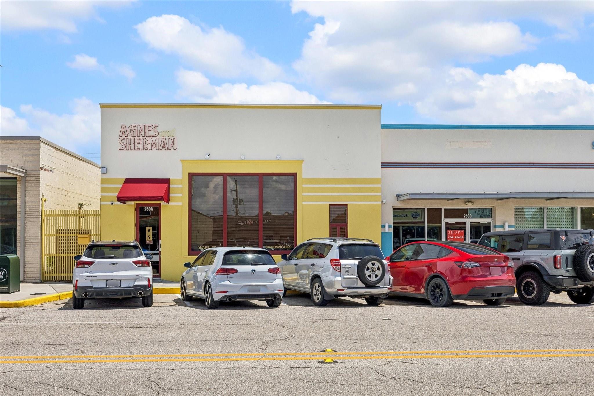 Agnes Sherman storefront with a red awning and parked cars.