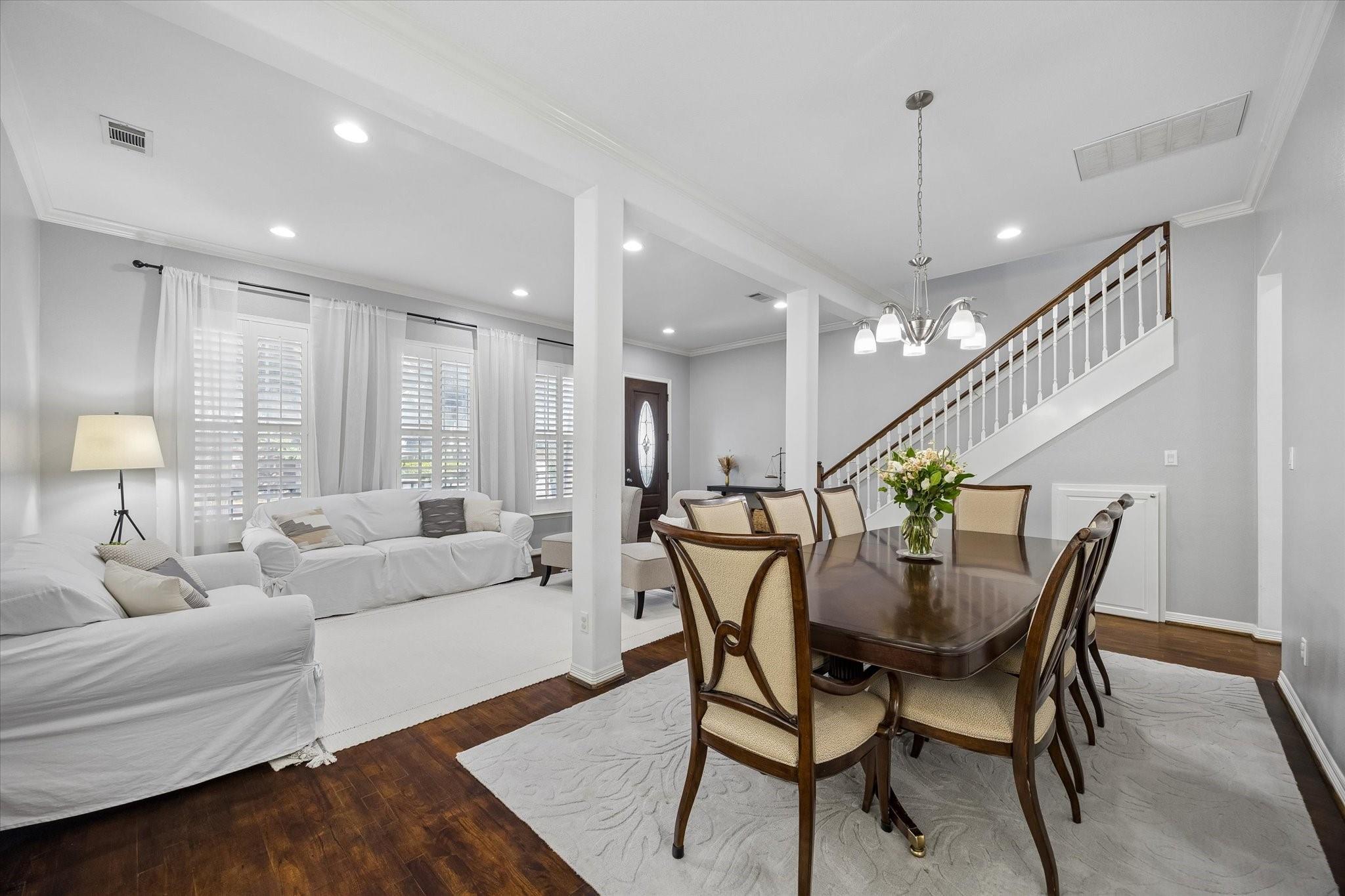 Open living and dining room with white sofas, a dark wood dining table, and a staircase.