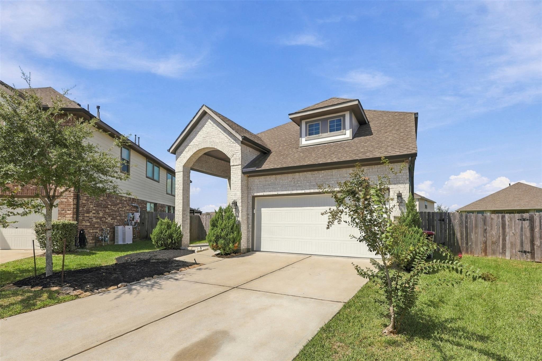 Two-story brick home with an arched entry, two-car garage, and landscaped front yard.