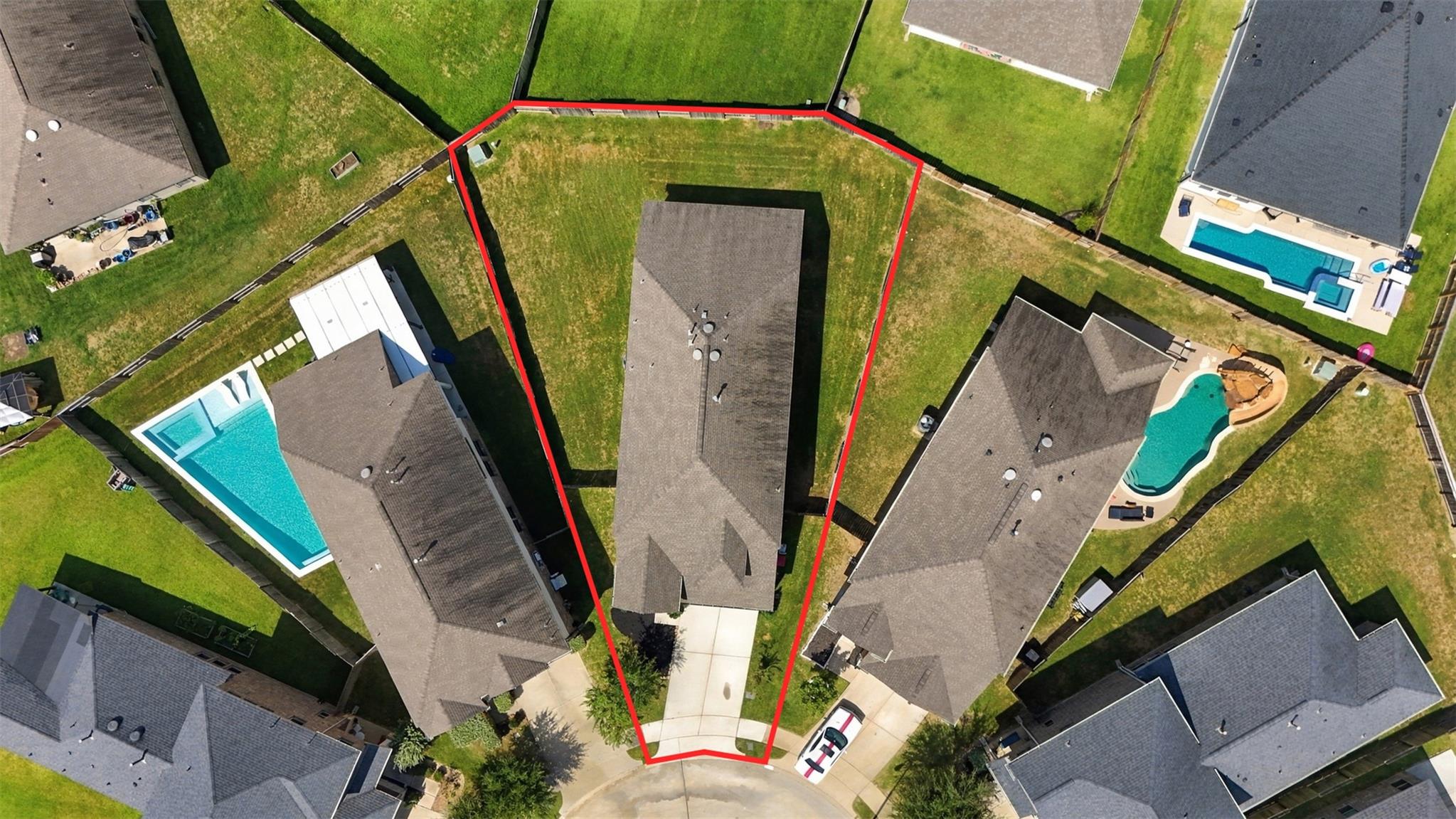 Aerial view of the outlined property lot, house, driveway, and neighboring homes.