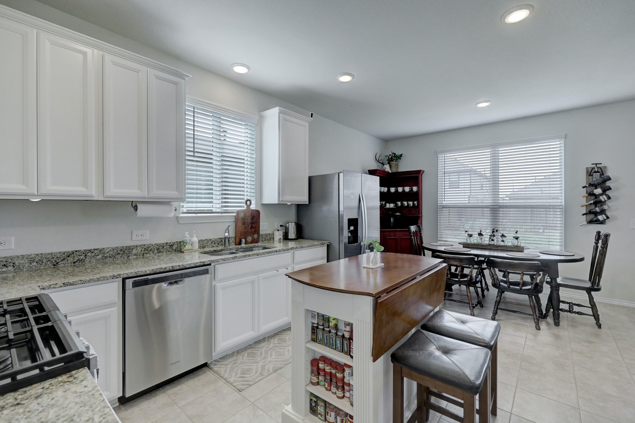 Kitchen with granite counters, stainless steel appliances, a wood-topped island, and an adjoining dining area.