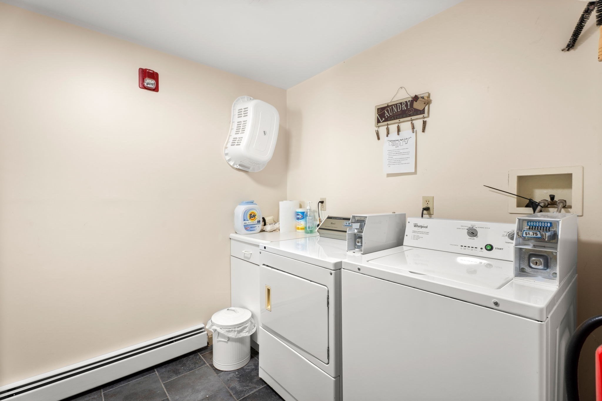 Laundry room with white commercial washers and dryers and coin-operated payment boxes.