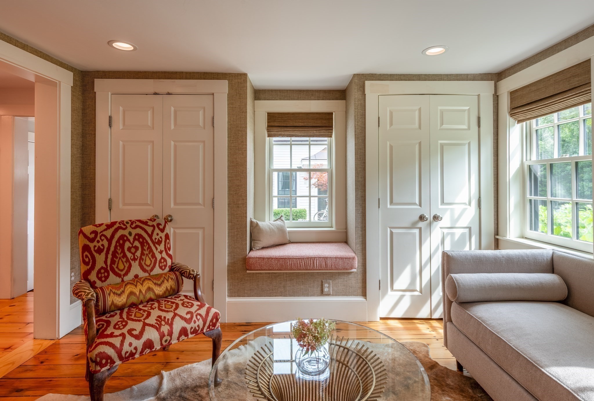 Sitting room with a red patterned armchair, gray sofa, and a built-in window seat.