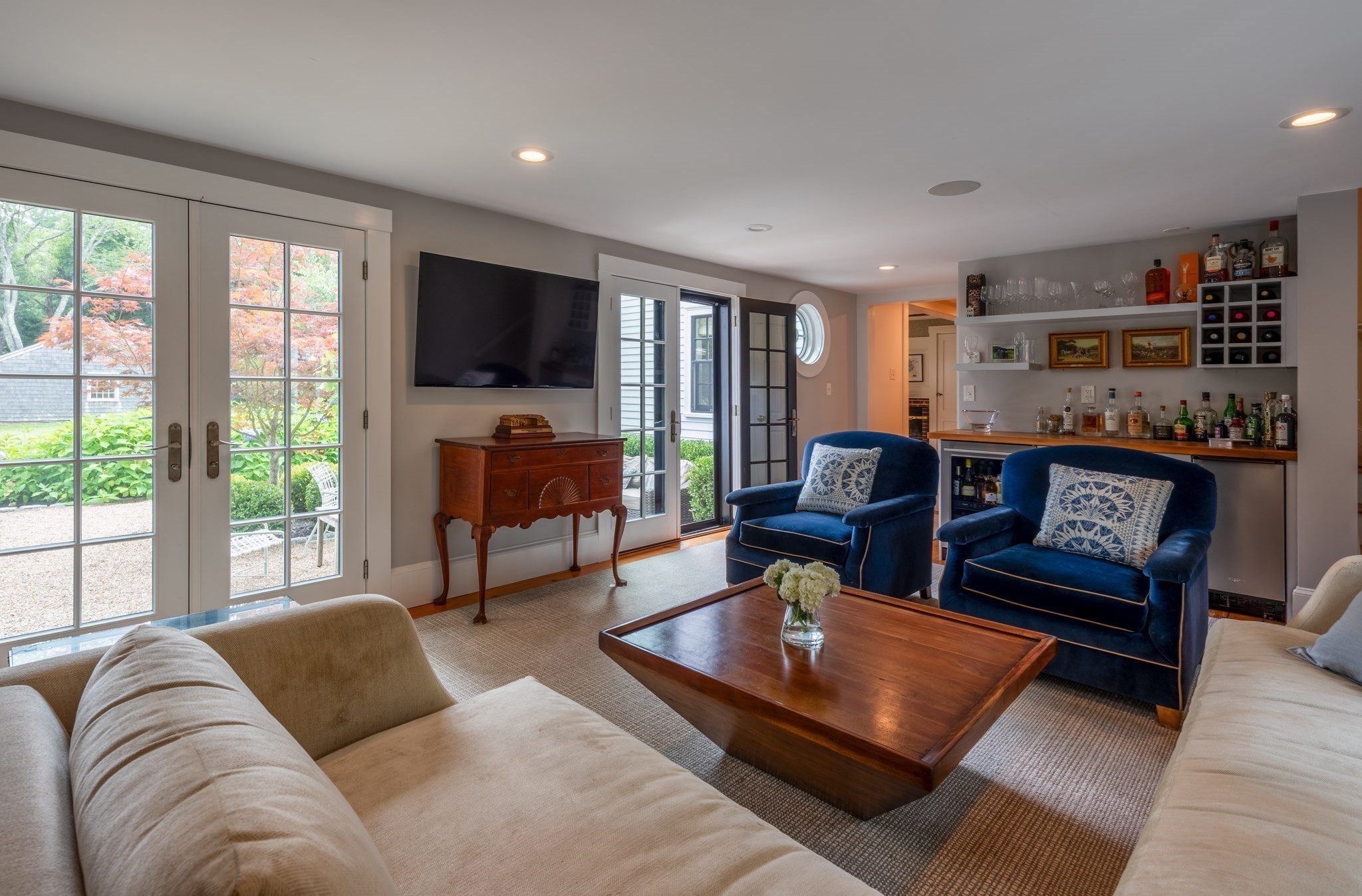 Living room with blue armchairs, French doors, and a built-in bar.