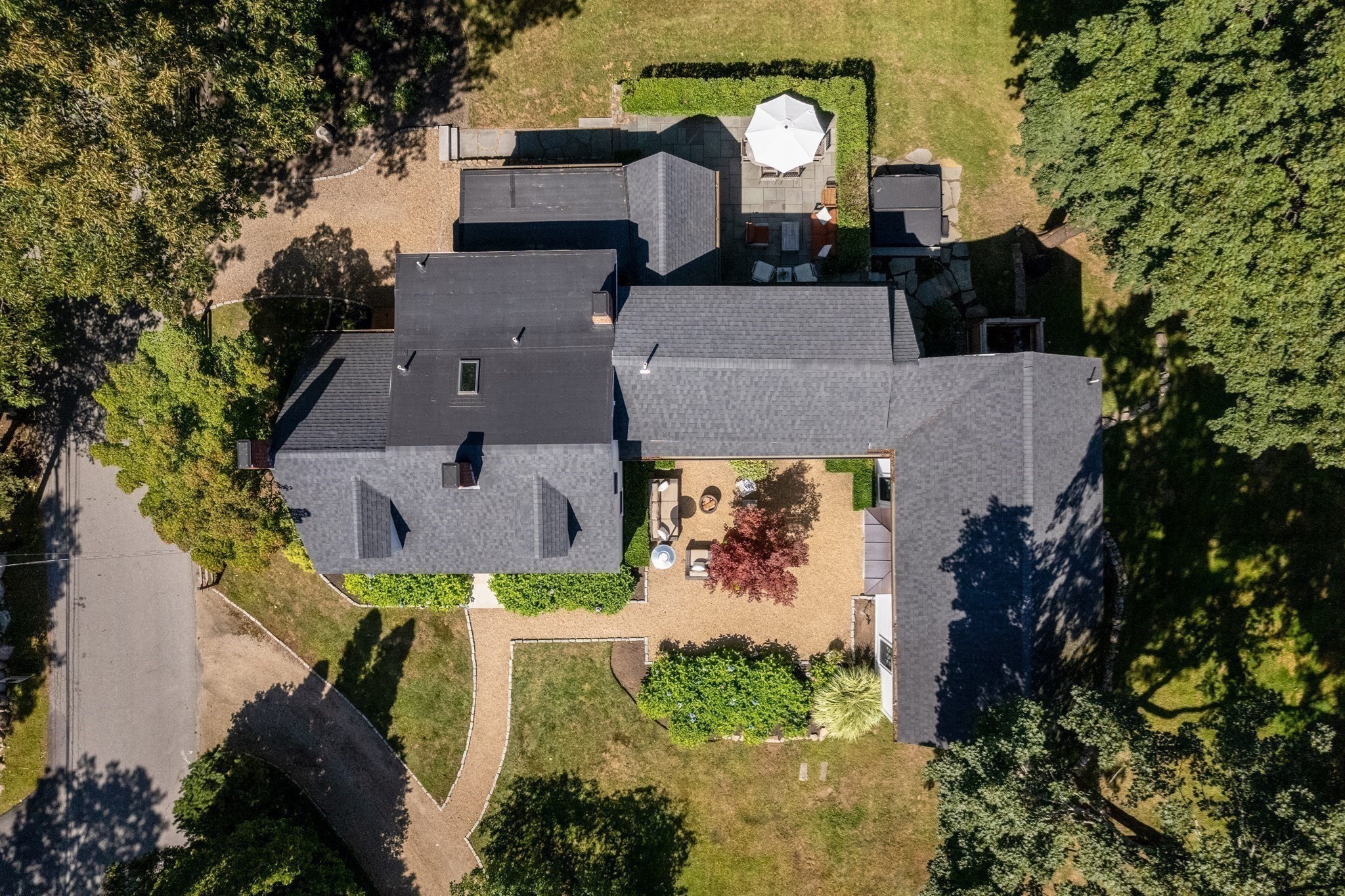 Aerial view of a large home with landscaped grounds and two furnished outdoor patios.