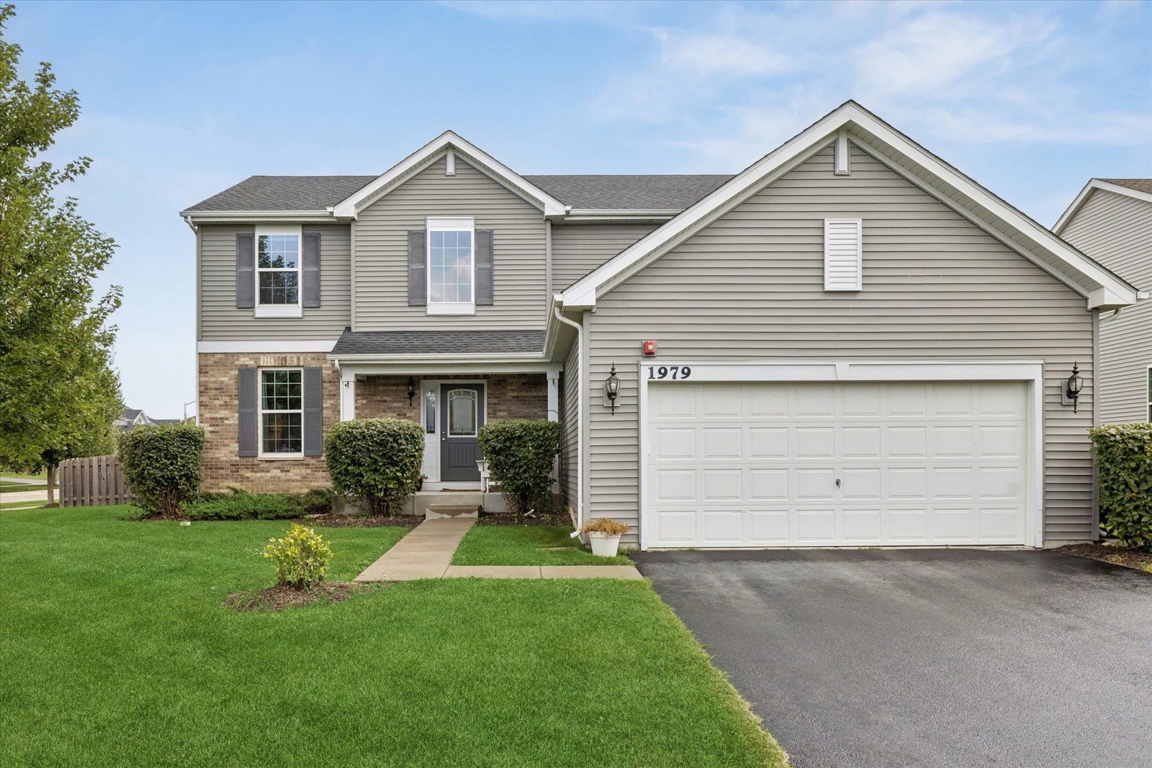 Two-story suburban home with gray siding, brick accents, and an attached double garage.